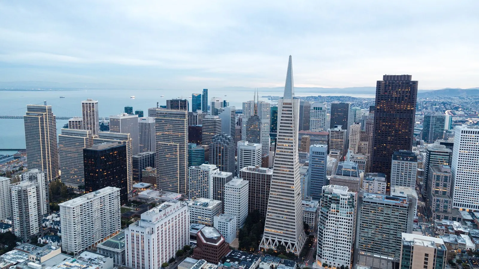 Aerial view of San Francisco's downtown towers, with the pointed Transamerica Pyramid, beside the bay.